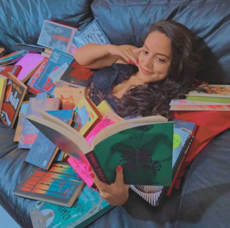 Mayara cercada por livros enquanto lê