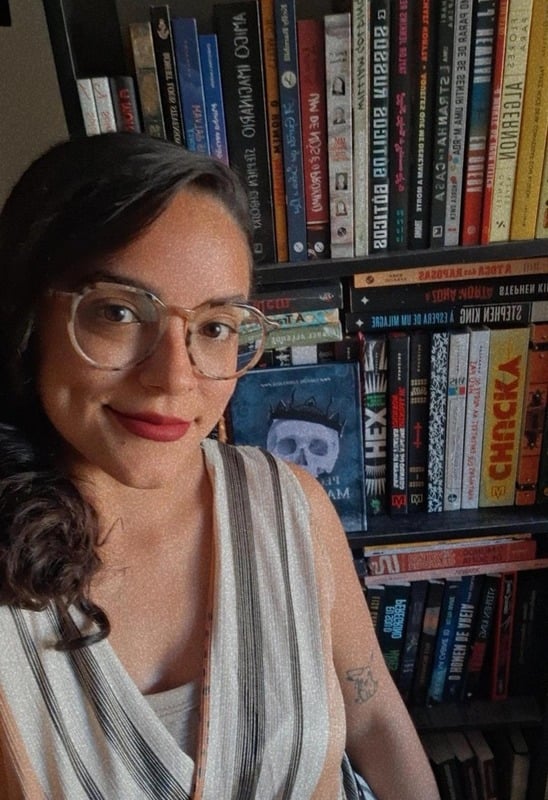 Mayara Trevizani em frente à sua estante de livros